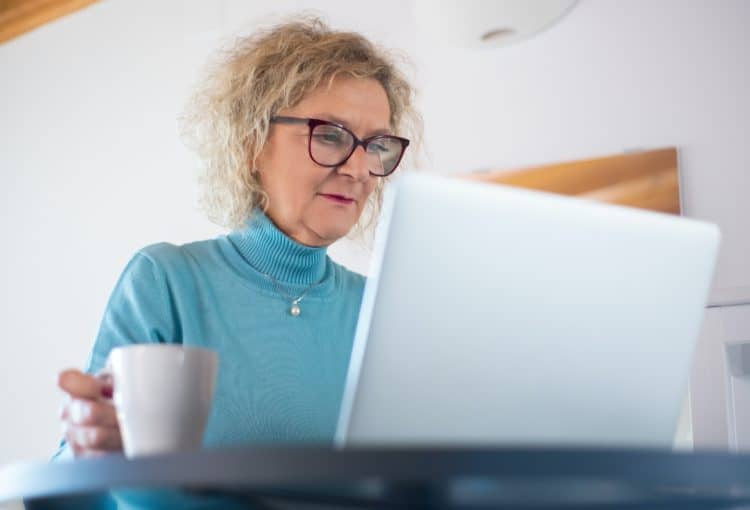 A person using their computer and drinking coffee