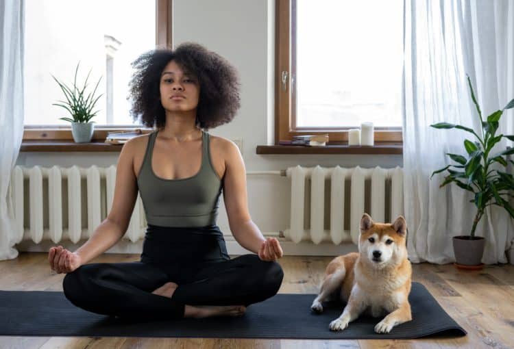 A person meditating with their dog