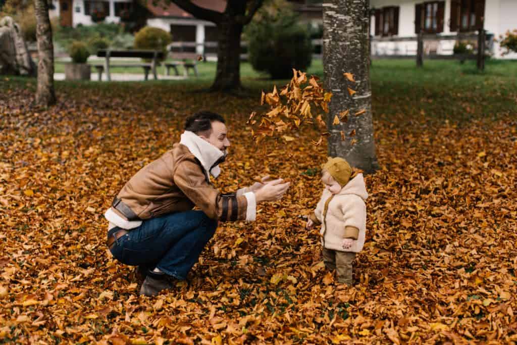 A person and a baby displaying a thankful mindset by playing in leaves
