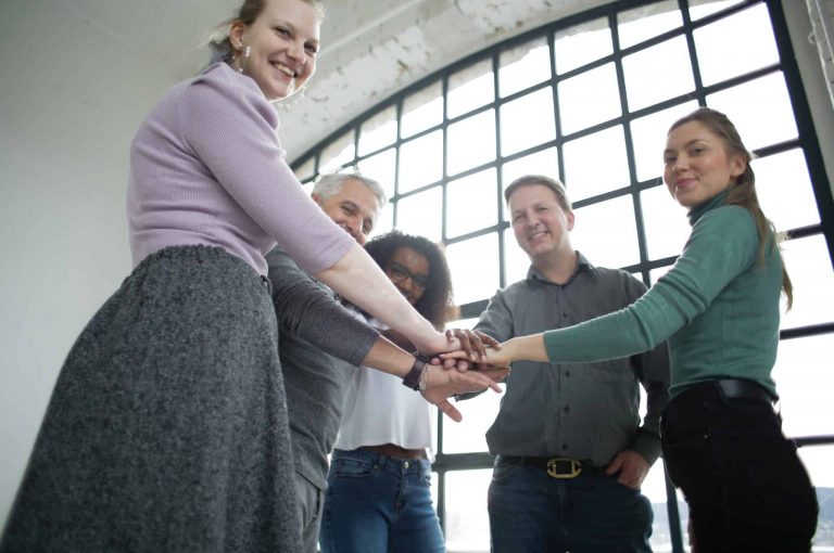 a group of people standing in a circle with their hands stacked on top of each other.