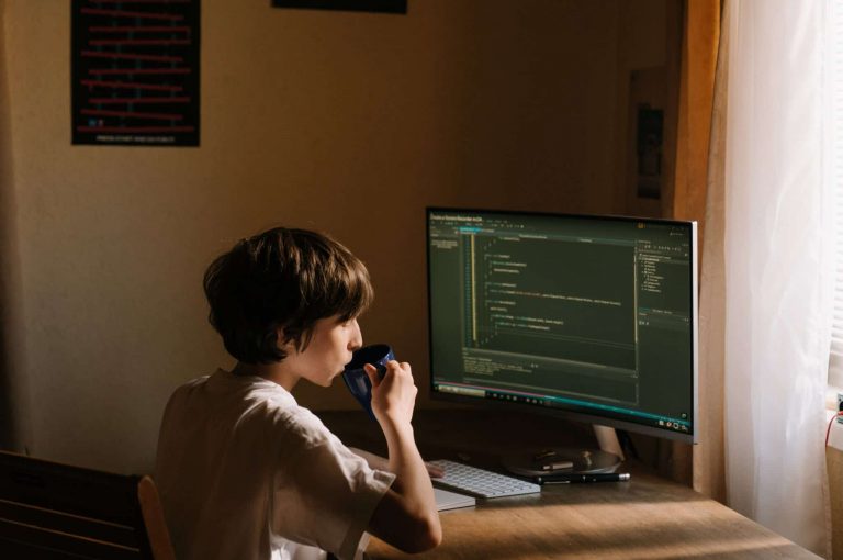a person drinking coffee and sitting in front of a computer