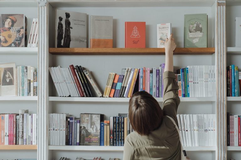 A person reaching for a book on a shelf
