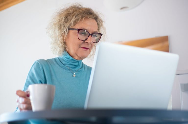 A person using their computer and drinking coffee