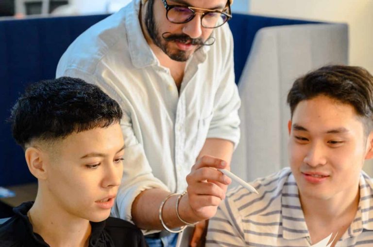 A group of three people pointing at a piece of paper and talking