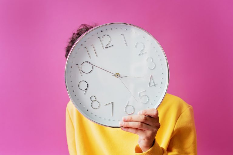 A person holding a clock in front of their face