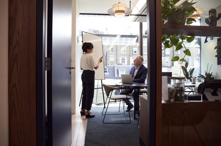 A woman teaching a male coworker