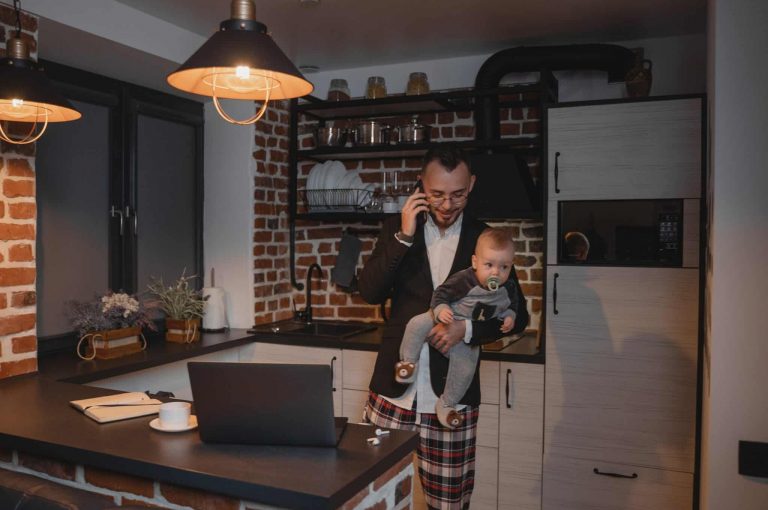 A person holding a baby while talking on the phone
